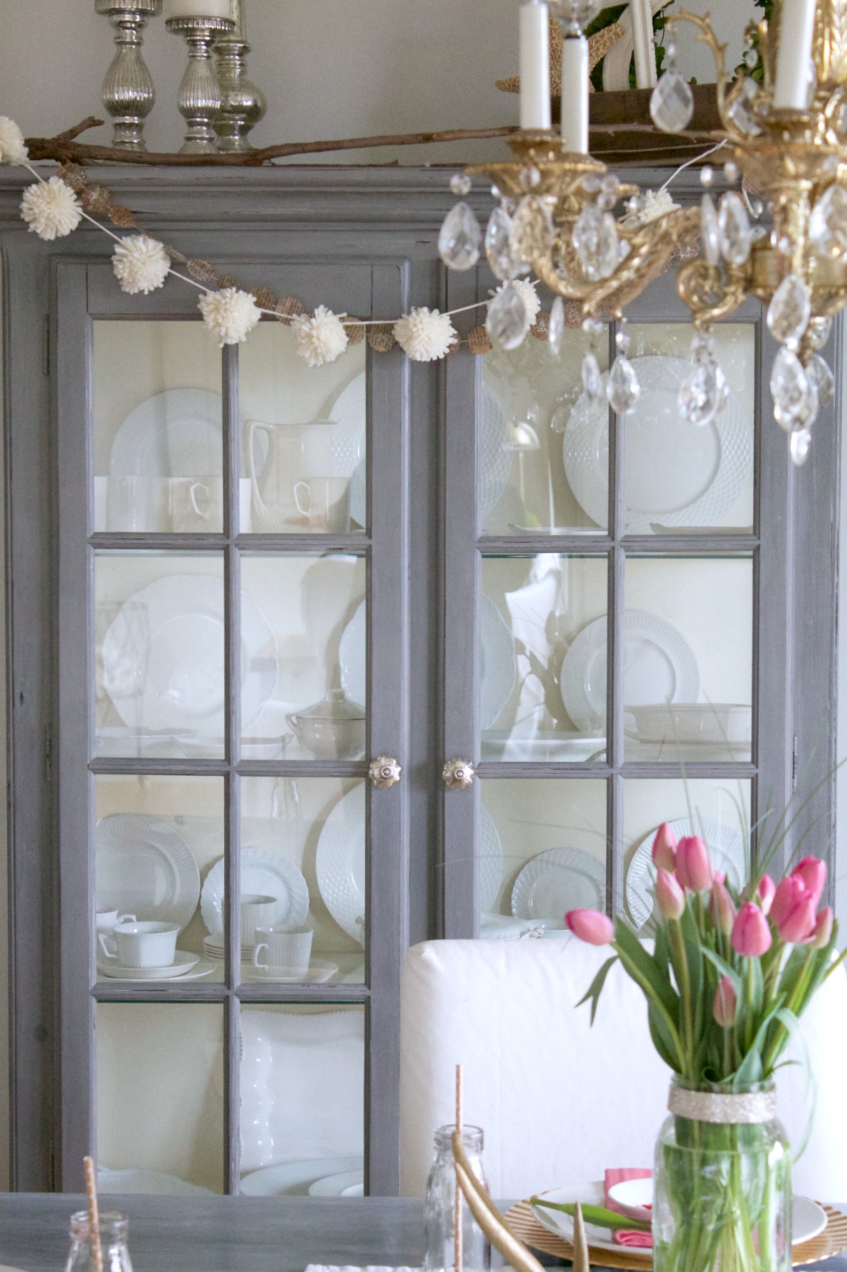 Gray painted china cabinet with white pom pom garland